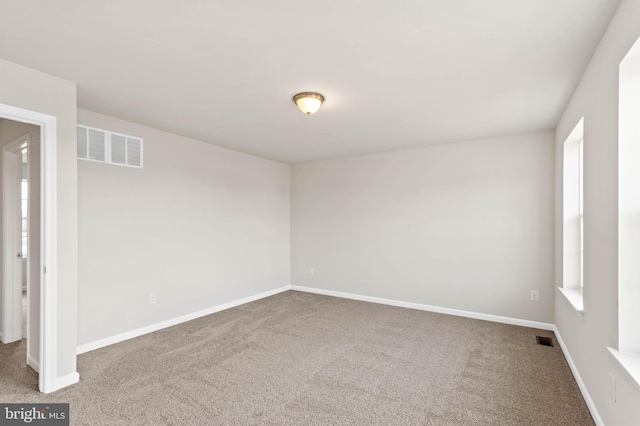 carpeted spare room with visible vents and baseboards