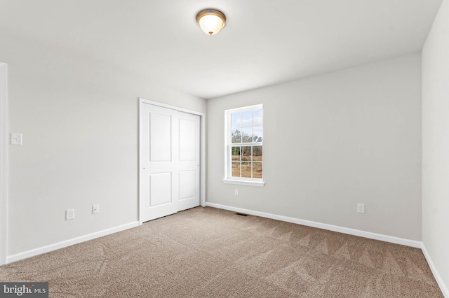 unfurnished bedroom featuring a closet, baseboards, visible vents, and carpet flooring