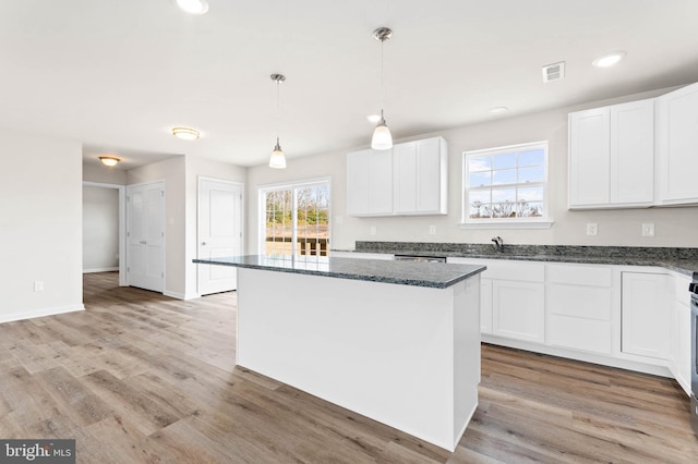 kitchen featuring white cabinetry, dark stone counters, light wood-style flooring, and visible vents