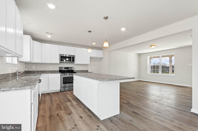 kitchen featuring visible vents, light wood-style flooring, a sink, light stone counters, and appliances with stainless steel finishes