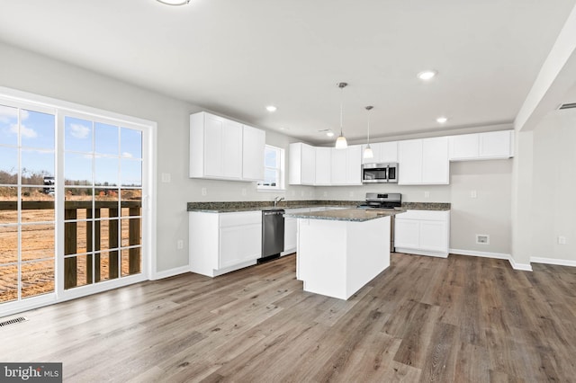 kitchen featuring recessed lighting, stainless steel appliances, wood finished floors, and white cabinetry