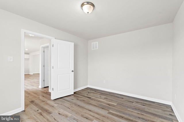 spare room featuring visible vents, baseboards, and wood finished floors