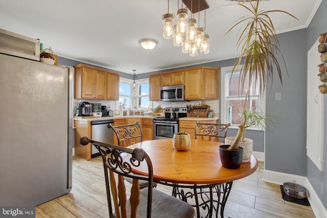 kitchen featuring baseboards, stainless steel appliances, light countertops, crown molding, and tasteful backsplash