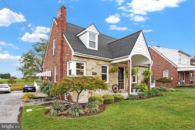 view of front of house with a chimney, stone siding, a shingled roof, and a front yard