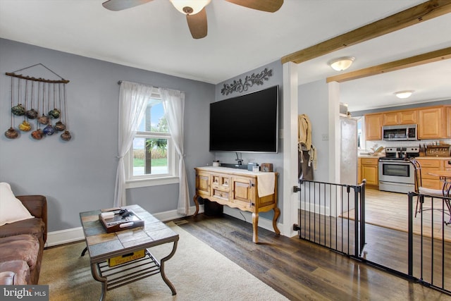 living room with a ceiling fan, baseboards, and wood finished floors