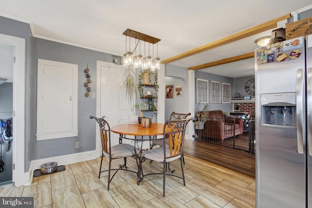 dining room featuring baseboards, wood tiled floor, beamed ceiling, ornamental molding, and a fireplace