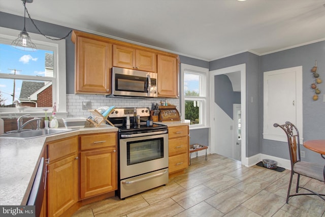 kitchen featuring a wealth of natural light, a sink, appliances with stainless steel finishes, light countertops, and decorative backsplash