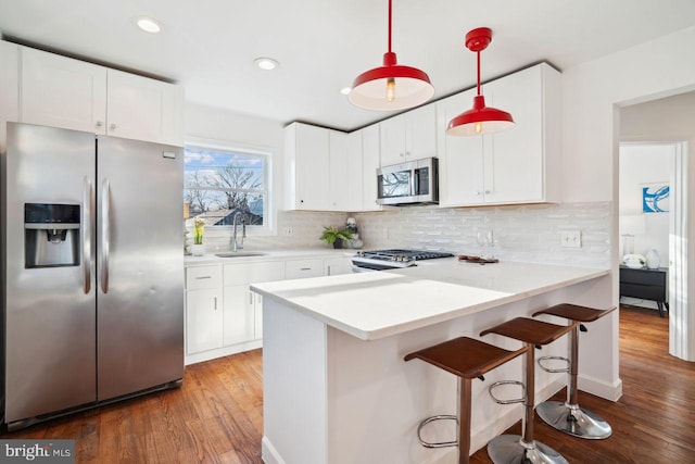 kitchen with a sink, a peninsula, decorative backsplash, and stainless steel appliances