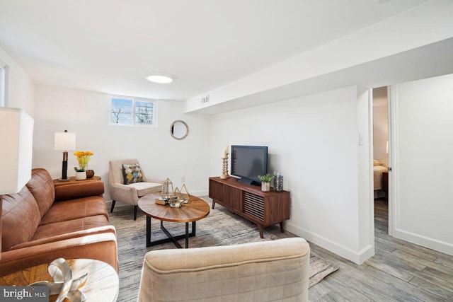 living room featuring visible vents, light wood-style floors, and baseboards