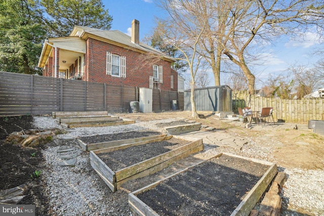 exterior space with a garden, an outdoor structure, fence private yard, and a shed