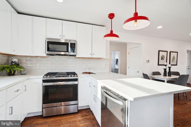 kitchen featuring light countertops, decorative backsplash, a peninsula, dark wood-style floors, and stainless steel appliances