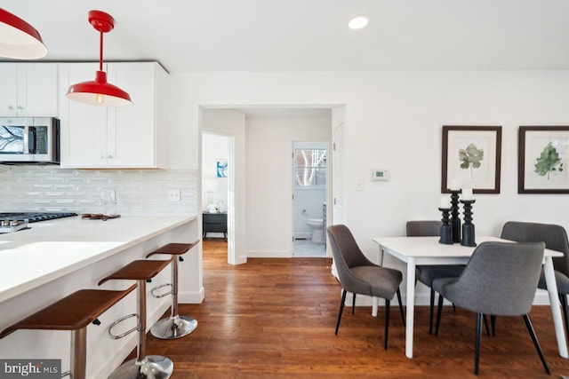 dining room with recessed lighting, baseboards, and dark wood-style flooring