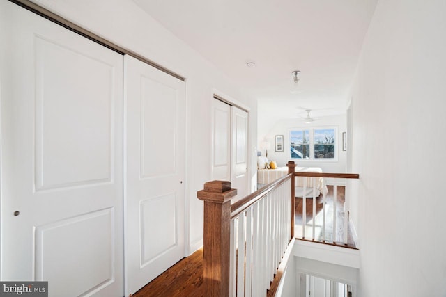 hallway featuring an upstairs landing and dark wood finished floors