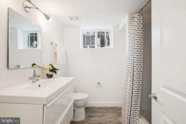 full bath with vanity, wood finished floors, baseboards, visible vents, and toilet