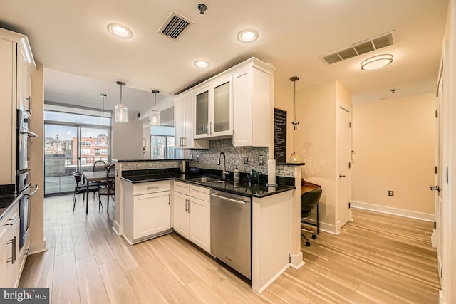 kitchen with tasteful backsplash, visible vents, a peninsula, stainless steel appliances, and a sink