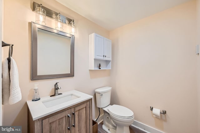 half bath with vanity, toilet, and baseboards