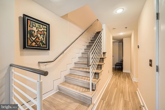 stairway with recessed lighting, baseboards, and wood finished floors