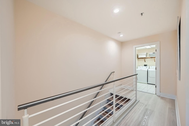 hallway with light wood-type flooring, an upstairs landing, washer and clothes dryer, recessed lighting, and baseboards