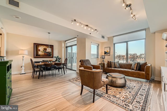 living area with light wood finished floors, visible vents, track lighting, and baseboards