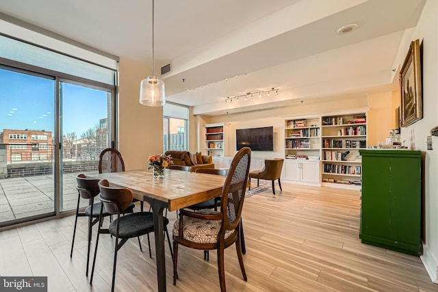 dining area with visible vents, rail lighting, a wall of windows, and light wood-type flooring