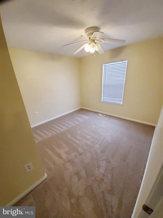 carpeted empty room featuring visible vents, baseboards, and ceiling fan