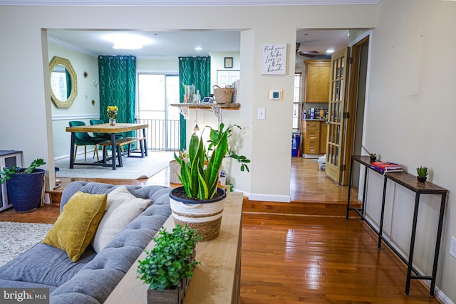 living area with baseboards, hardwood / wood-style floors, and ornamental molding