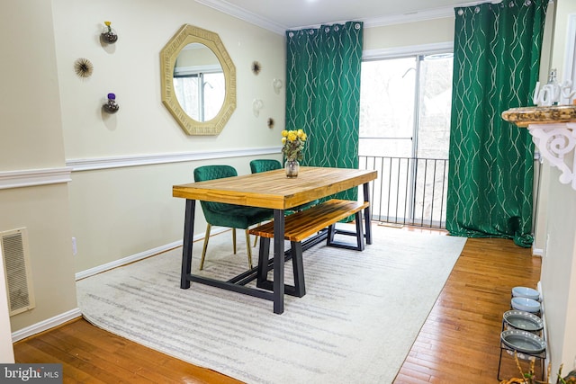 dining space with visible vents, crown molding, baseboards, and hardwood / wood-style floors