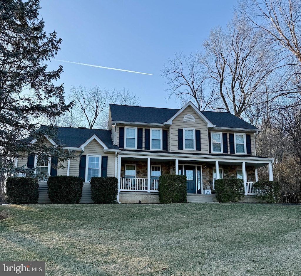 colonial inspired home featuring a porch and a front lawn