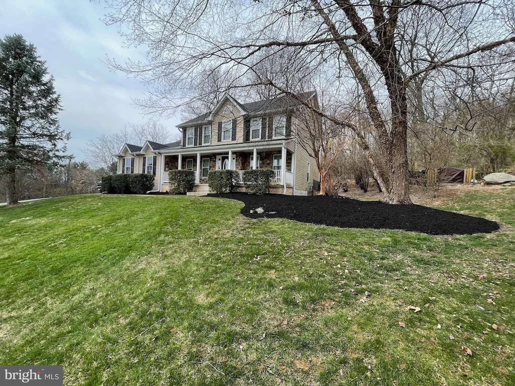 colonial home featuring covered porch and a front lawn