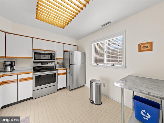 kitchen featuring stainless steel appliances, white cabinetry, visible vents, and light countertops