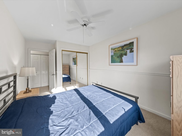 carpeted bedroom featuring a ceiling fan, baseboards, and two closets