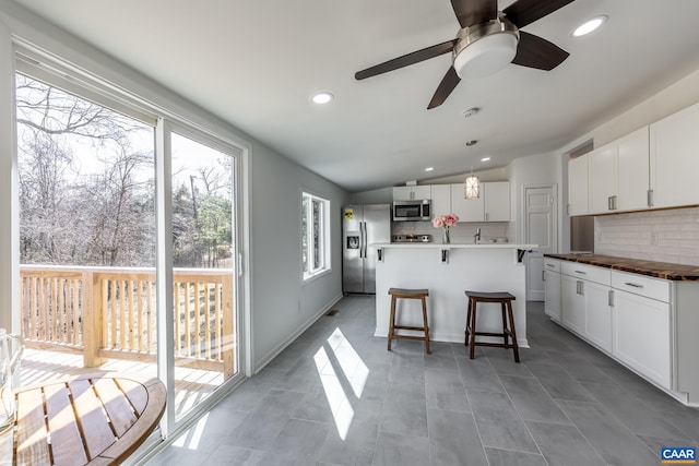 kitchen with stainless steel appliances, lofted ceiling, backsplash, and a breakfast bar