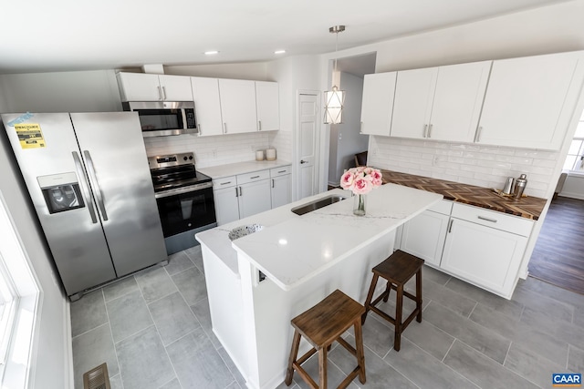 kitchen featuring visible vents, a sink, stainless steel appliances, white cabinets, and tasteful backsplash