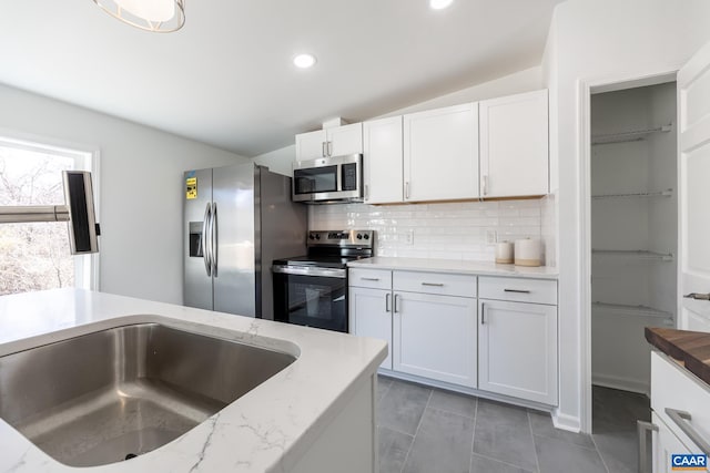 kitchen with white cabinetry, lofted ceiling, tasteful backsplash, and appliances with stainless steel finishes