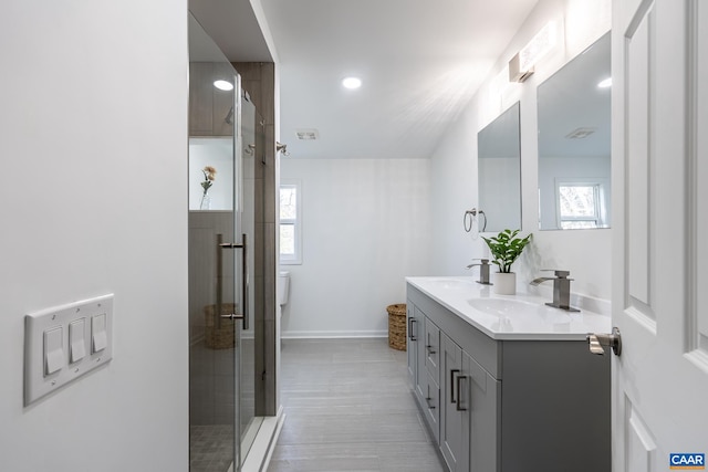 full bath with double vanity, baseboards, a shower stall, and a sink