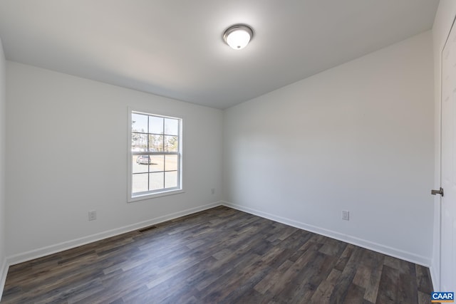 unfurnished room featuring dark wood finished floors, baseboards, and visible vents