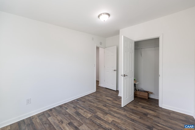 unfurnished bedroom with a closet, baseboards, and dark wood-style flooring