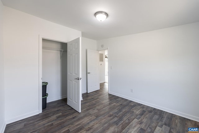 unfurnished bedroom featuring baseboards, dark wood-style flooring, and a closet