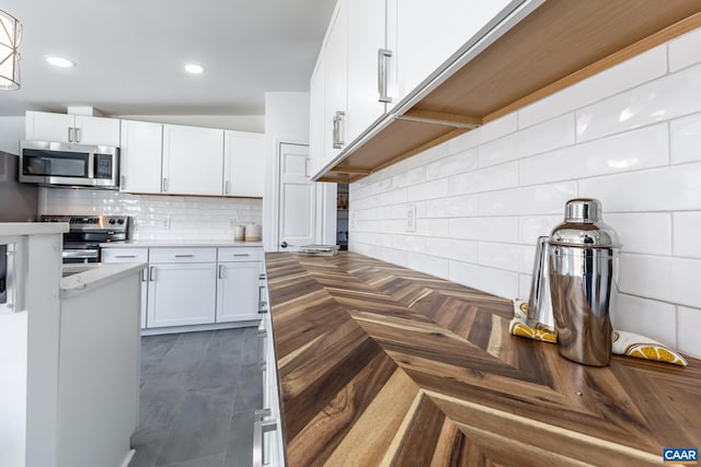 kitchen with decorative backsplash, recessed lighting, white cabinetry, and appliances with stainless steel finishes