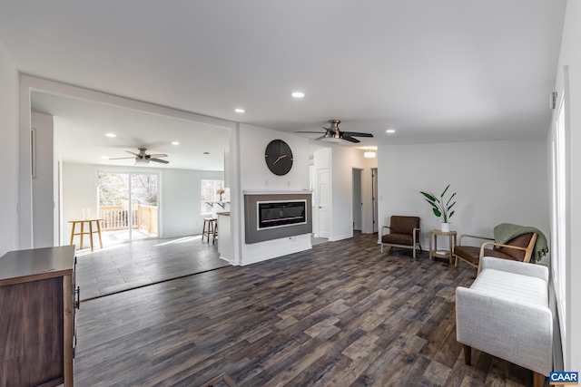 living room featuring a glass covered fireplace, recessed lighting, dark wood-style floors, and ceiling fan