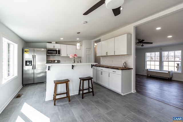 kitchen with white cabinetry, visible vents, a kitchen bar, and stainless steel appliances