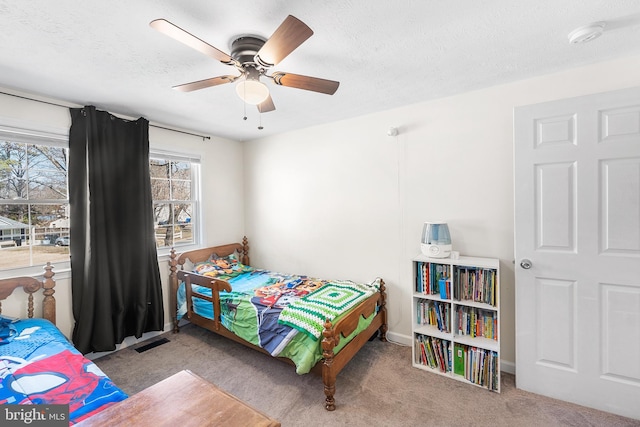 bedroom with ceiling fan, visible vents, carpet floors, and a textured ceiling