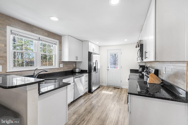 kitchen with a sink, appliances with stainless steel finishes, light wood-style flooring, and white cabinetry