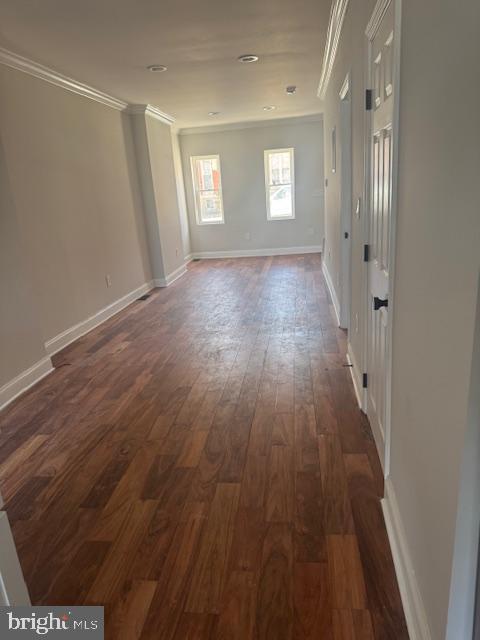 empty room with baseboards, dark wood-type flooring, and ornamental molding