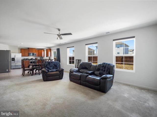 living room featuring visible vents, light carpet, baseboards, and a ceiling fan