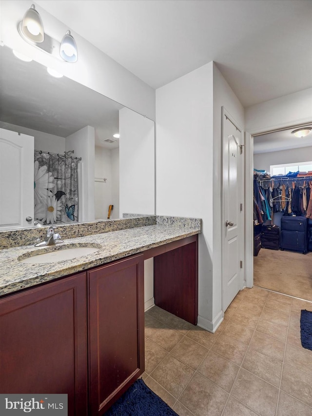 full bath with tile patterned floors, a shower with shower curtain, vanity, and a walk in closet