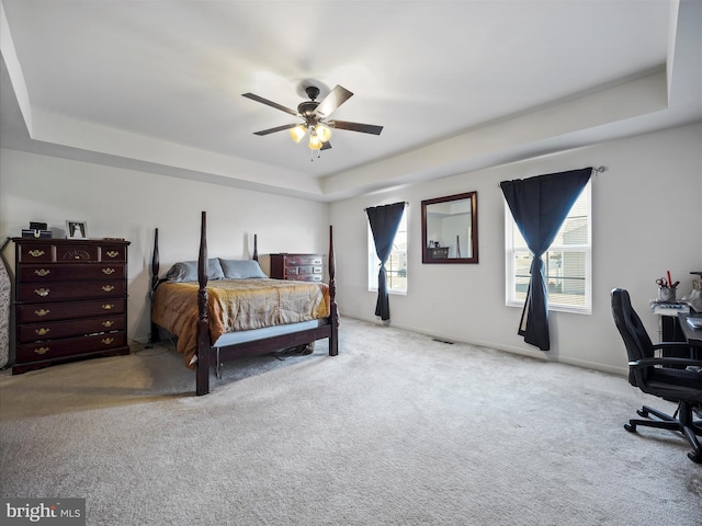 carpeted bedroom with baseboards, a raised ceiling, and ceiling fan