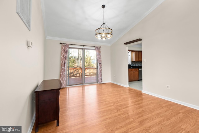 spare room featuring baseboards, light wood finished floors, lofted ceiling, an inviting chandelier, and crown molding