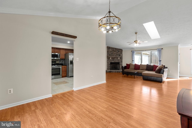 unfurnished living room featuring light wood-type flooring, a stone fireplace, a skylight, crown molding, and baseboards