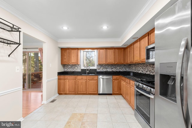 kitchen featuring a sink, backsplash, appliances with stainless steel finishes, and ornamental molding